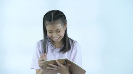Educational concepts. The girl is taking notes in her notebook on a white background. 4k Resolution.の写真素材