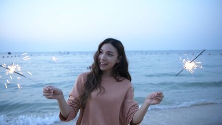 Holiday concept. Asian girls playing fun fireworks on the beach. 4k Resolution.の写真素材
