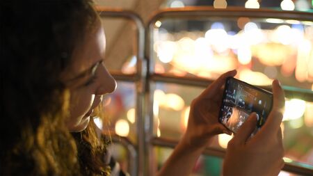 Holiday concept. A beautiful girl taking a high-angle photo on the ferris wheel. 4k Resolution.