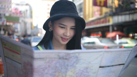 Travel concept. Beautiful girls are reading the map on the roadside. 4k Resolution.の写真素材