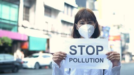 Concept of pollution prevention. The girl wearing a mask is holding a sign indicating the message. 4k Resolution.の写真素材