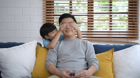 Family concept. The son is making his father freak in the living room. 4k Resolution.の写真素材