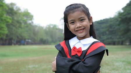 Educational concepts. The girl wearing the graduation dress stands confidently in the garden. 4k Resolution.の写真素材