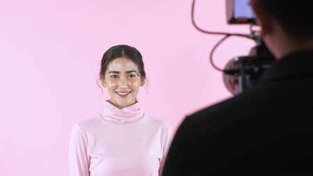 Beauty concept. A beautiful woman modeling in a studio on a pink background