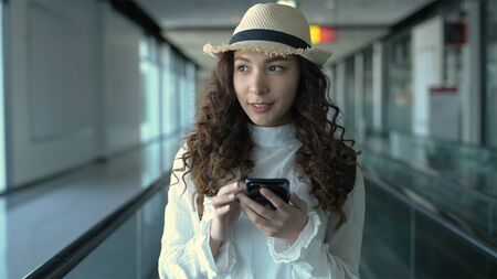 Travel concept. A girl playing on the phone while traveling at the airport. 4k Resolution.