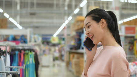 Shopping concepts. An Asian woman is talking on the phone in the mall. 4k Resolution.