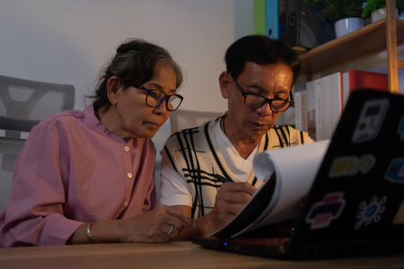 Caucasian couple working on computer at home. They are checking investment information on the internet.の写真素材