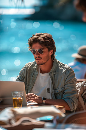 Caucasian man in casual clothes using laptop Working at a desk on the beach.の素材