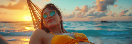 Asian woman in bikini lying in a hammock at sunset on the beach.の素材