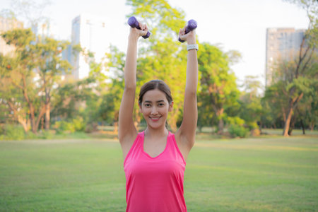 Woman exercising outdoors with dumbbells.