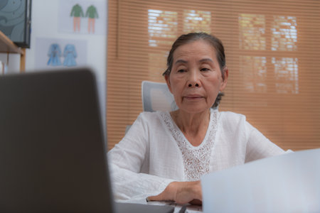 Elderly woman working on a laptop at home.の写真素材