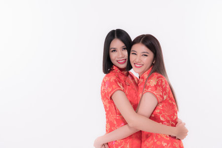 Two women in vibrant red dresses embrace joyfully, showcasing cultural tradition and friendship.の写真素材