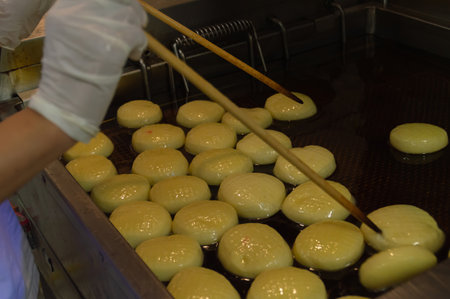 A chef skillfully frying golden dough balls in hot oil, creating a delicious culinary delight.の写真素材