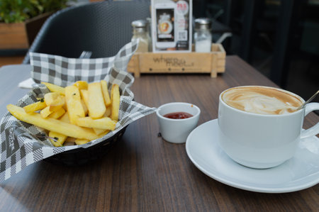 A plate of golden fries served with a cup of coffee, capturing a perfect snack moment at a cozy cafe.の写真素材