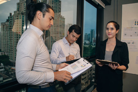 Three professionals collaborate in a modern office environment, engaging in discussion and planning.の写真素材