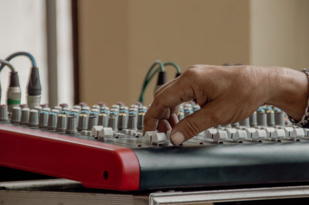 A close-up of a hand adjusting knobs on a sound mixing console, showcasing precision and creativity in audio production.の写真素材