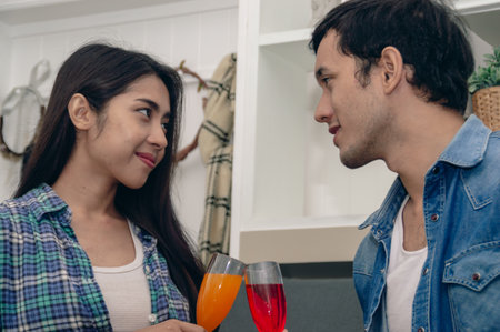 A joyful couple enjoying colorful drinks together, showcasing love and connection in a modern kitchen setting.の写真素材