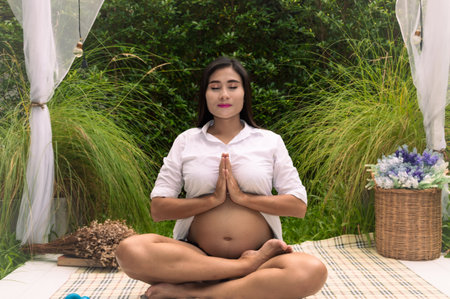 A serene pregnant woman practicing mindfulness in nature, promoting peace and tranquility in motherhood.の写真素材