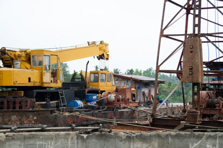 Heavy machinery and equipment on a construction site in a rural area under overcast skies.の写真素材