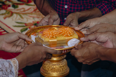 A group of hands offering a beautifully decorated tray, symbolizing unity and tradition in cultural ceremonies.の写真素材