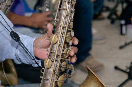 Close-up of a musician&#39;s hand playing a saxophone, showcasing the instrument&#39;s intricate keys and details.の写真素材