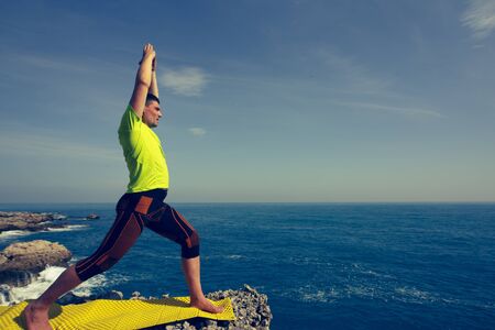 Young man practicing yoga and meditation at the sea.の写真素材