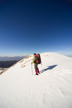 A man in a winter hike in the mountains with a backpack.の写真素材