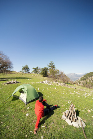 Man camping with a tent in the mountains in the summer on a sunny day.の写真素材