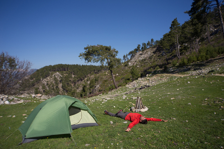 Man camping with a tent in the mountains in the summer on a sunny day.の写真素材