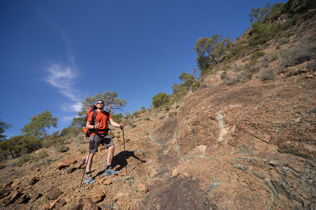 A man with a backpack hiking in the mountains on a sunny day.の写真素材