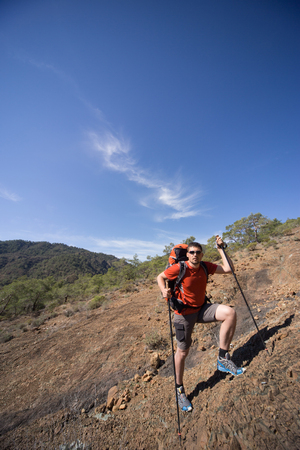 A man with a backpack hiking in the mountains on a sunny day.の写真素材