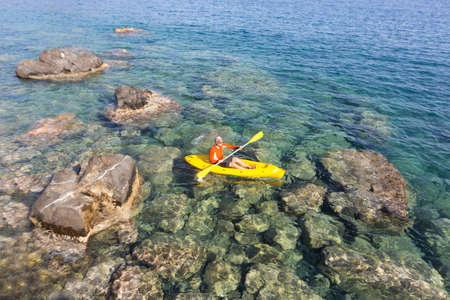 A man traveling by canoe along the coast in the summer.の写真素材