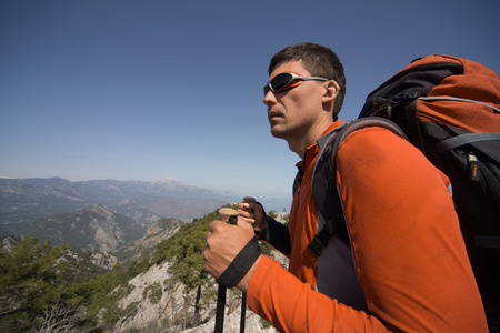 A man with a backpack hiking in the mountains on a sunny day.の写真素材