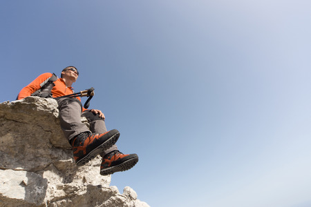 A man with a backpack hiking in the mountains on a sunny day.の写真素材