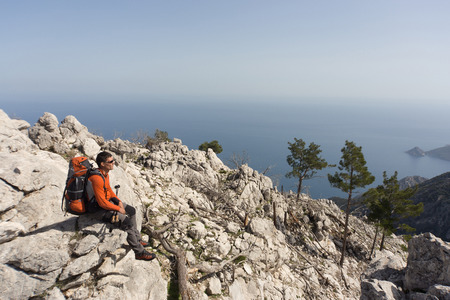 Young man with backpack on a mountain top on a sunny day.の写真素材