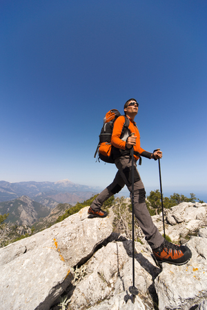 Young man with backpack on a mountain top on a sunny day.の写真素材