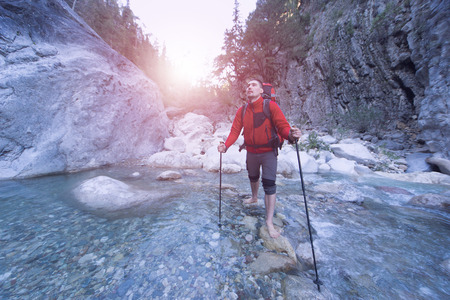 Young man with a backpack to move a mountain river.の写真素材