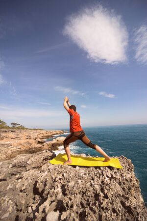 young man doing yoga exercises on the beach.の写真素材