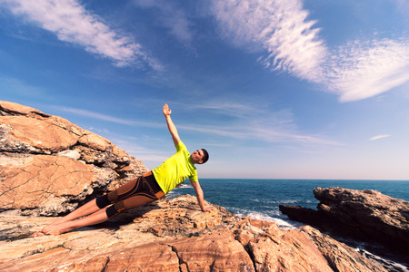 young man doing yoga exercises on the beach.の写真素材