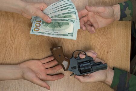 Transfers of money in exchange for a gun under certain conditions, sitting at the table.の写真素材