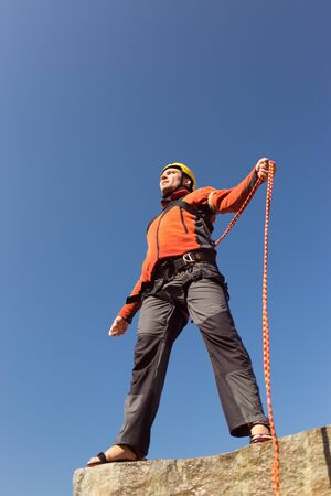 Man jumping off a cliff with a rope on a sunny day.の写真素材