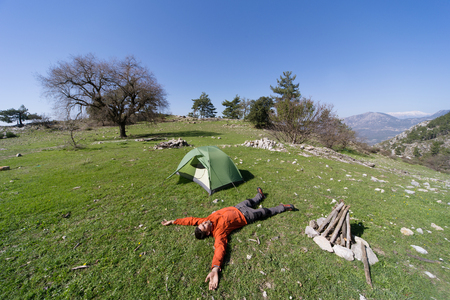 Man camping with a tent in the mountains in the summer on a sunny day.の写真素材