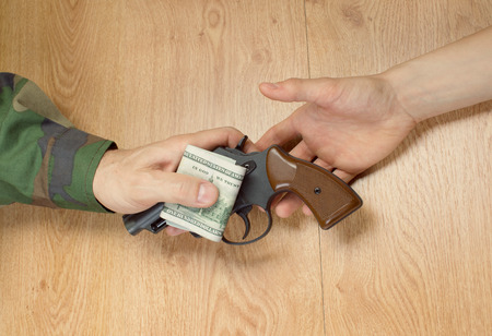 Transfers of money in exchange for a gun under certain conditions, sitting at the table.の写真素材