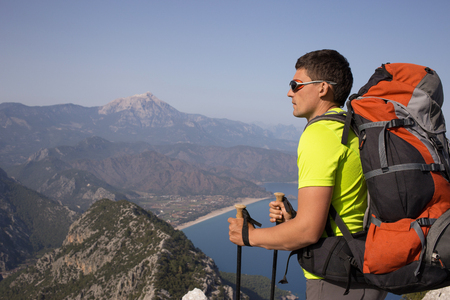 Young man with backpack on a mountain top on a sunny day.の写真素材