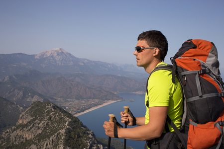 Young man with backpack on a mountain top on a sunny day.の写真素材