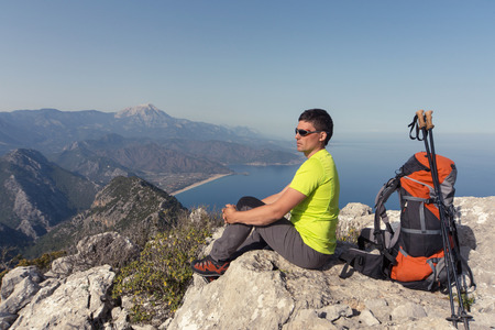 Young man with backpack on a mountain top on a sunny day.の写真素材