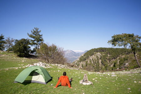 Man camping with a tent in the mountains in the summer on a sunny day.の写真素材