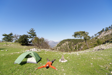 Man camping with a tent in the mountains in the summer on a sunny day.の写真素材