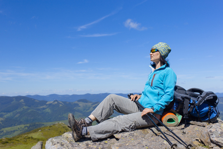 Girl with a backpack in the mountains of the campaign against the blue sky.の写真素材
