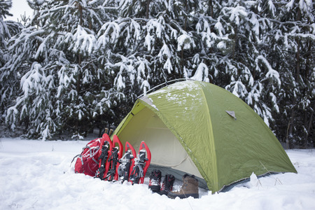 Camping in the winter campaign of winter with snowshoes and tent.